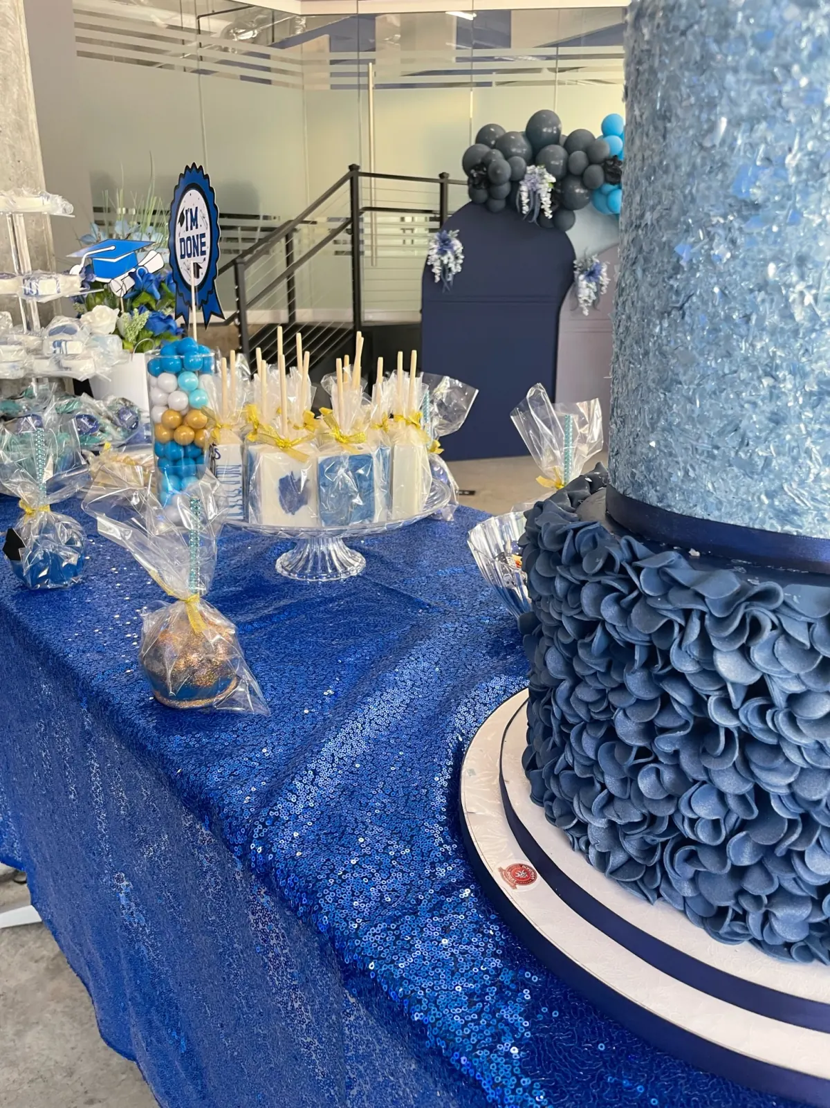 Graduation dessert table with cake and treats on a sequined runner