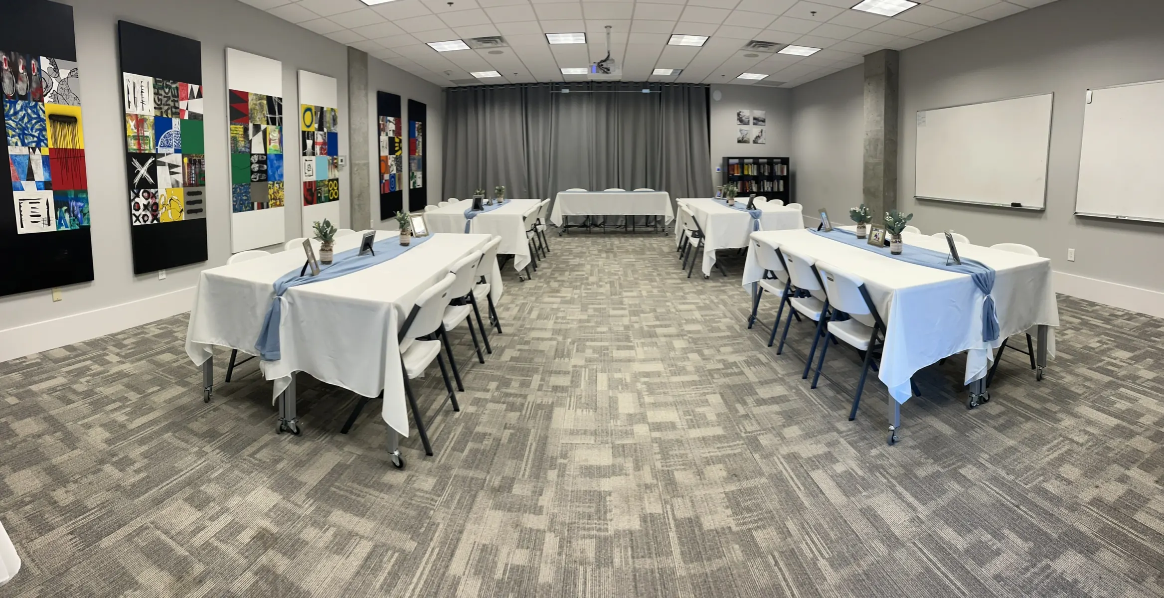 Training room set with white tables, blue runners, and gallery walls